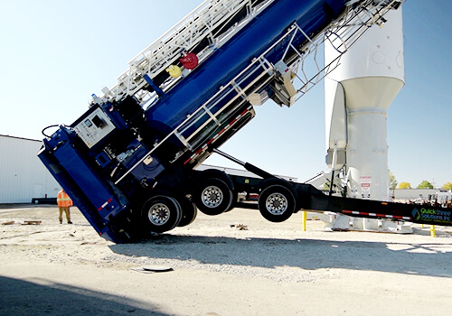 An image of a quickload 300 tower being stood in place from a quickstand trailer.